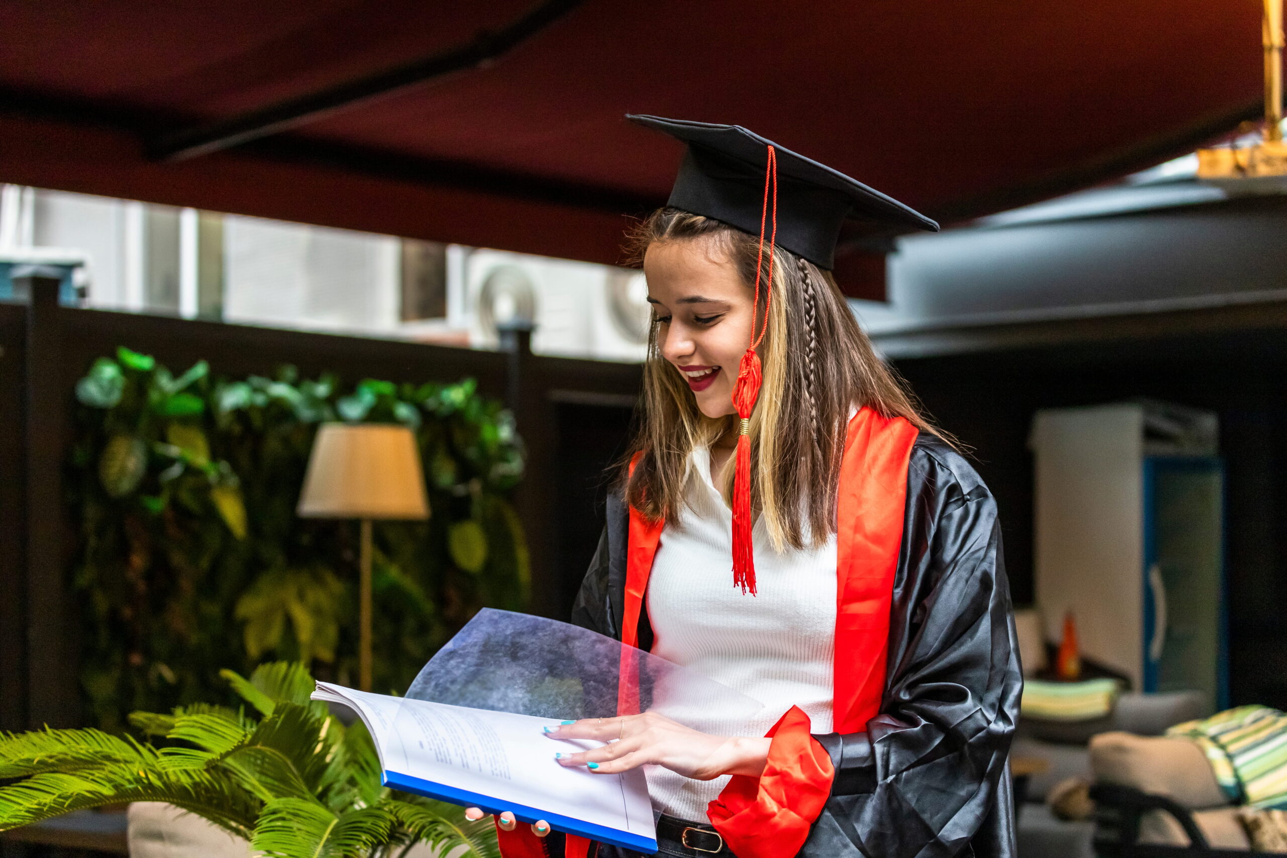 young-student-wearing-graduation-cape-looking-her-notebook